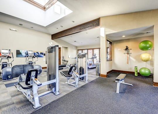 A gym with a variety of equipment including weights and exercise balls.
