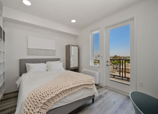 a white bedroom with a bed and a door to a balcony