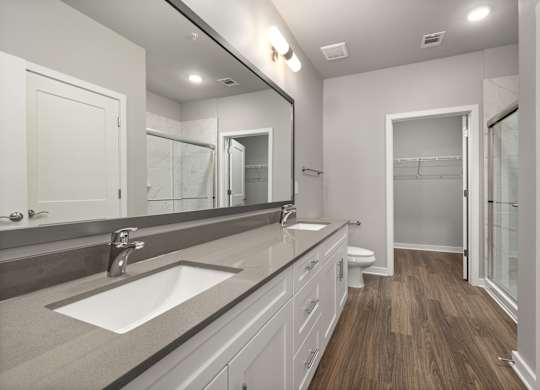 A bathroom with a sink, mirror, and wood flooring.