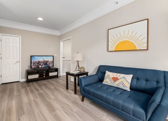 a living room with a blue couch and a tv at Mariners Crossing, Raleigh North Carolina
