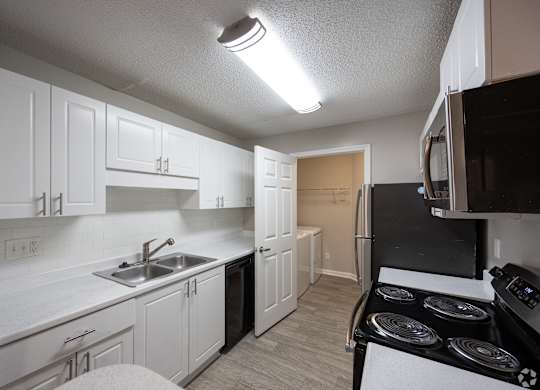 A kitchen with white cabinets and a black stove top.