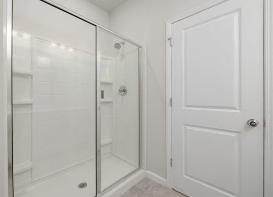 a white bathroom with a shower and a door