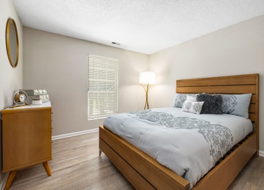 a bedroom with a bed and a dresser with a lamp at View at Lake Lynn, North Carolina, 27613