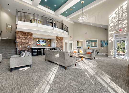 the lobby of a clubhouse with couches and chairs and a fireplace
