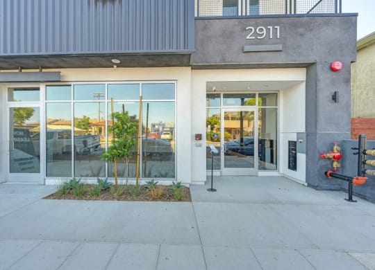 the front of a building with glass doors and a fire hydrant