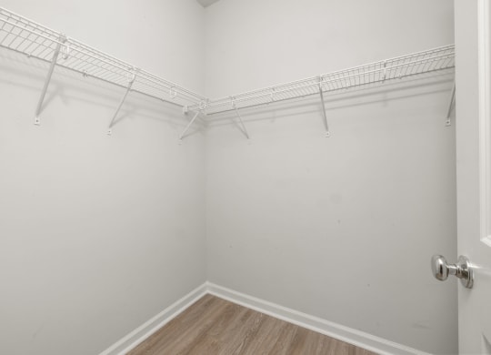 a room with white walls and a white closet with hanging racks