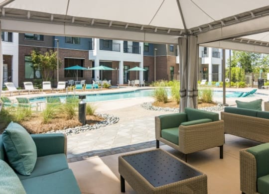 a lobby with couches and chairs and a pool with umbrellas
