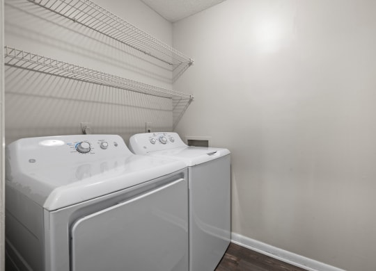 a washer and dryer in a laundry room with white walls and a shelf