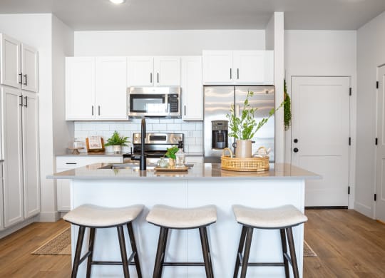 a kitchen with white cabinets and a large island with three stools