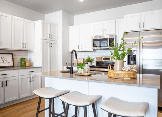 a kitchen with white cabinets and a large island with two stools