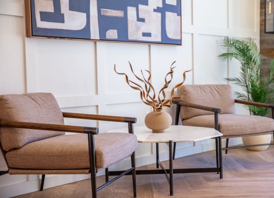 a living room with two chairs and a table with a vase