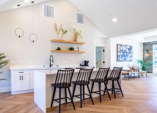 a kitchen with a bar and stools in a living room with a dining area