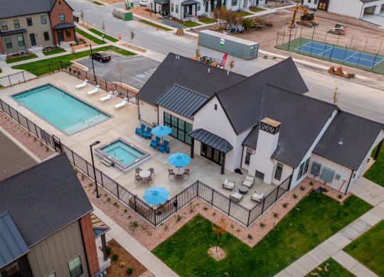 an aerial view of a house with two pools and patio furniture