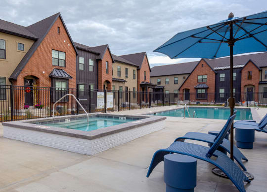 our apartments at the district feature a pool and patio with chairs and an umbrella