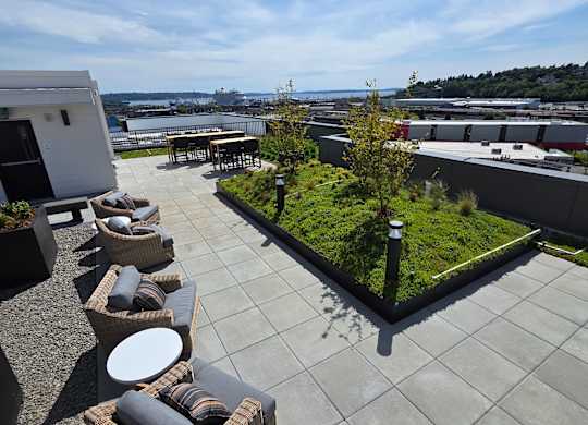 A patio with a table, chairs, and a planter.