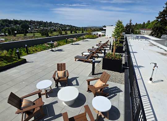 A patio with chairs and tables overlooks a city.