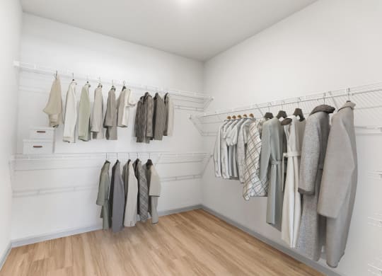a walk in closet with white walls and wooden flooring