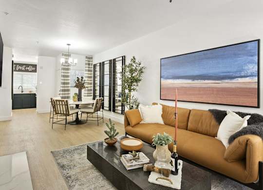 A living room with a brown couch, a coffee table, and a large painting on the wall.