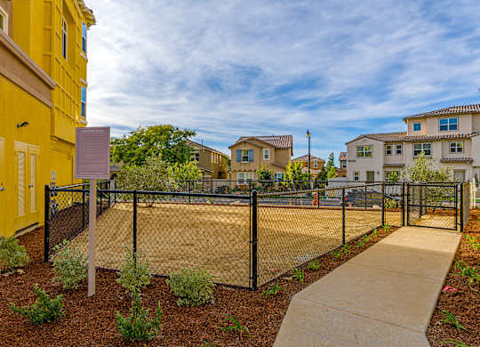 A yellow building with a black fence and a sign in front of it.