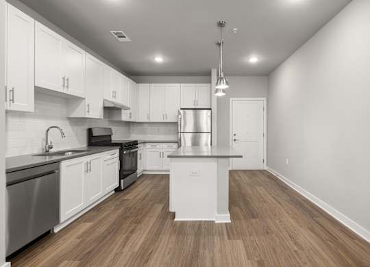 A modern kitchen with white cabinets and a wooden floor.