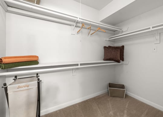 a laundry room with white walls and shelves and a small trash can