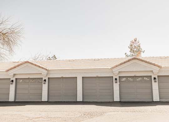 A house with a grey roof and four garages.