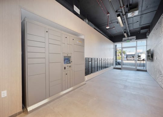 a hallway with a row of white lockers and a door to a building