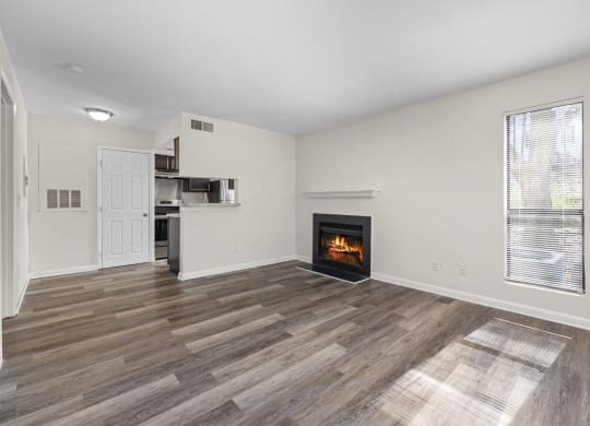 an empty living room with a fireplace and a kitchen