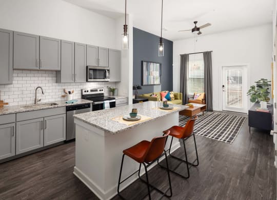 an open kitchen and living room with an island and chairs