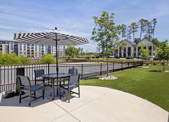 A patio with a table and chairs under a striped umbrella.
