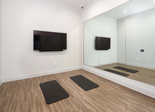 a yoga room with mirrors and yoga mats and a television on the wall