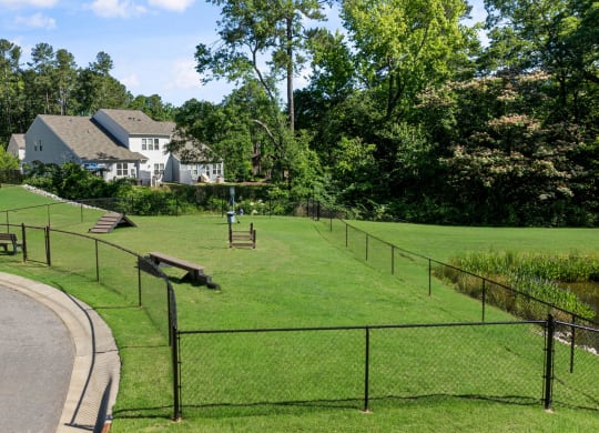 a park with a fenced in area and houses in the background