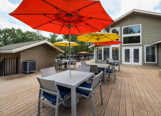 a large deck with tables, chairs and umbrellas