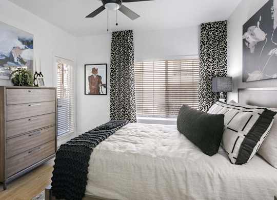 A bedroom with a bed, a dresser, and a ceiling fan.