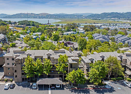an aerial view of a building in a city with trees and a lake