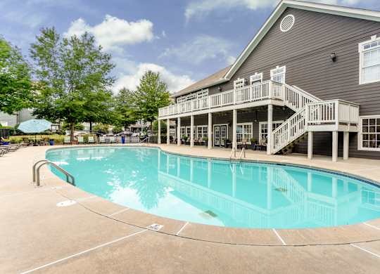 A large outdoor swimming pool with a deck and stairs leading to a building.