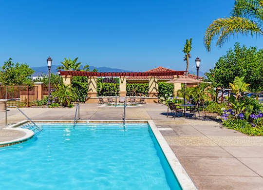 A pool surrounded by a fence and a patio area.