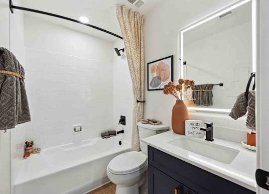 A bathroom with a white tub, sink, and toilet.
