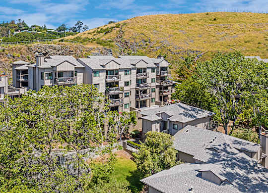 a view of the condos from above with trees and a hill
