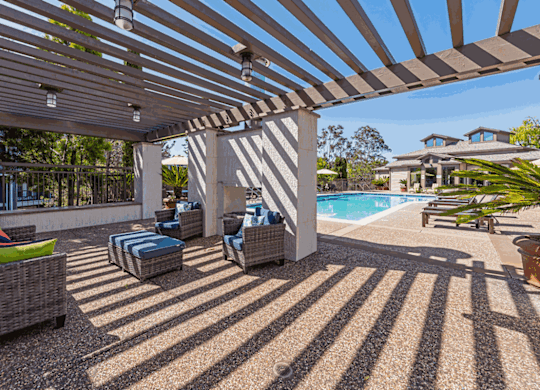 a covered patio with chairs and a pool