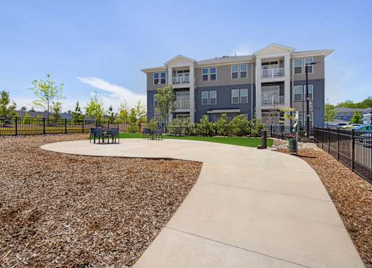 A concrete walkway leads to a building with a fenced in yard.