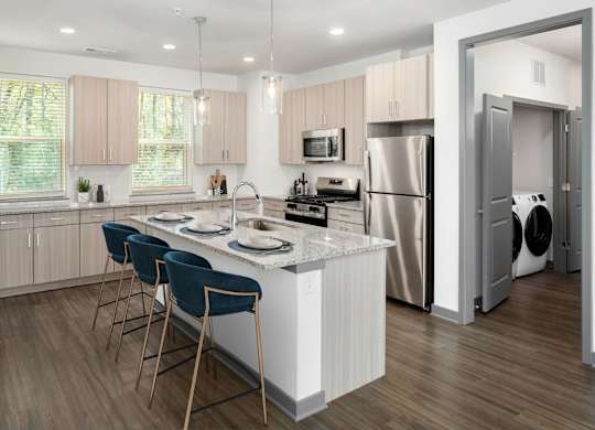 A modern kitchen with a white island and blue chairs.