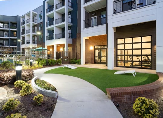 an exterior view of an apartment building with green grass and a sidewalk