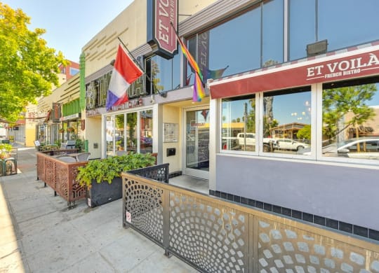 a street view of a restaurant with flags on the sidewalk
