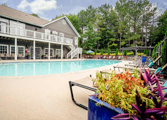 A pool area with a building and a planter.