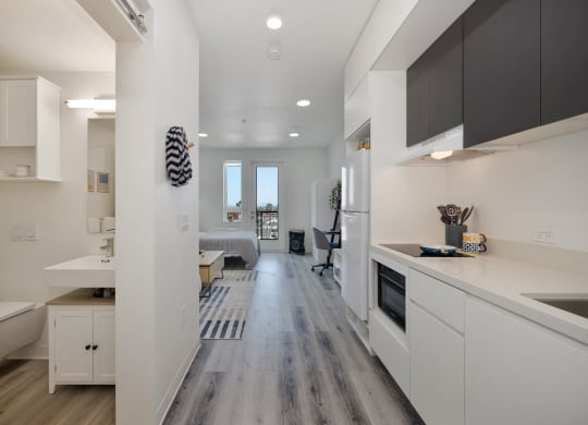 a kitchen and living room with white cabinets and wood floors