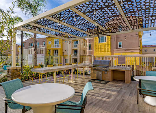 A patio with a table and chairs under a blue and white canopy.