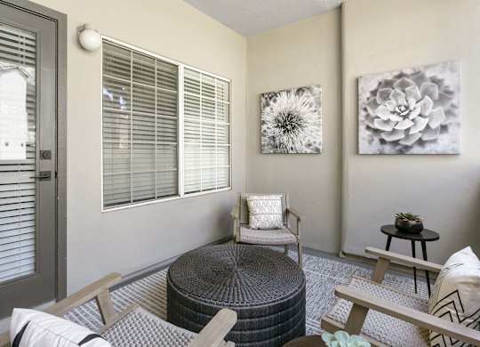 A living room with a grey ottoman, a grey chair, and a grey table.