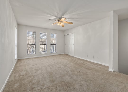 an empty living room with a ceiling fan and window