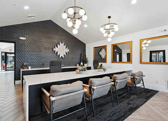 A modern kitchen with a long island and grey chairs.